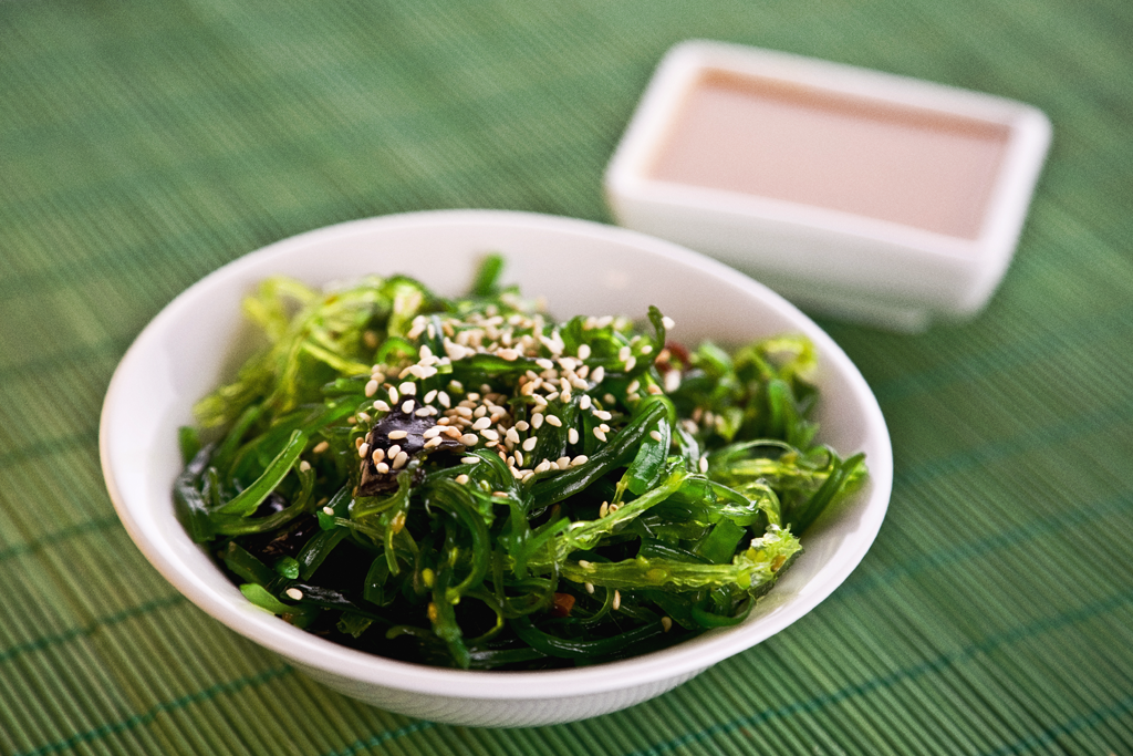 Seaweed salad in a white bowl on a placemat. 