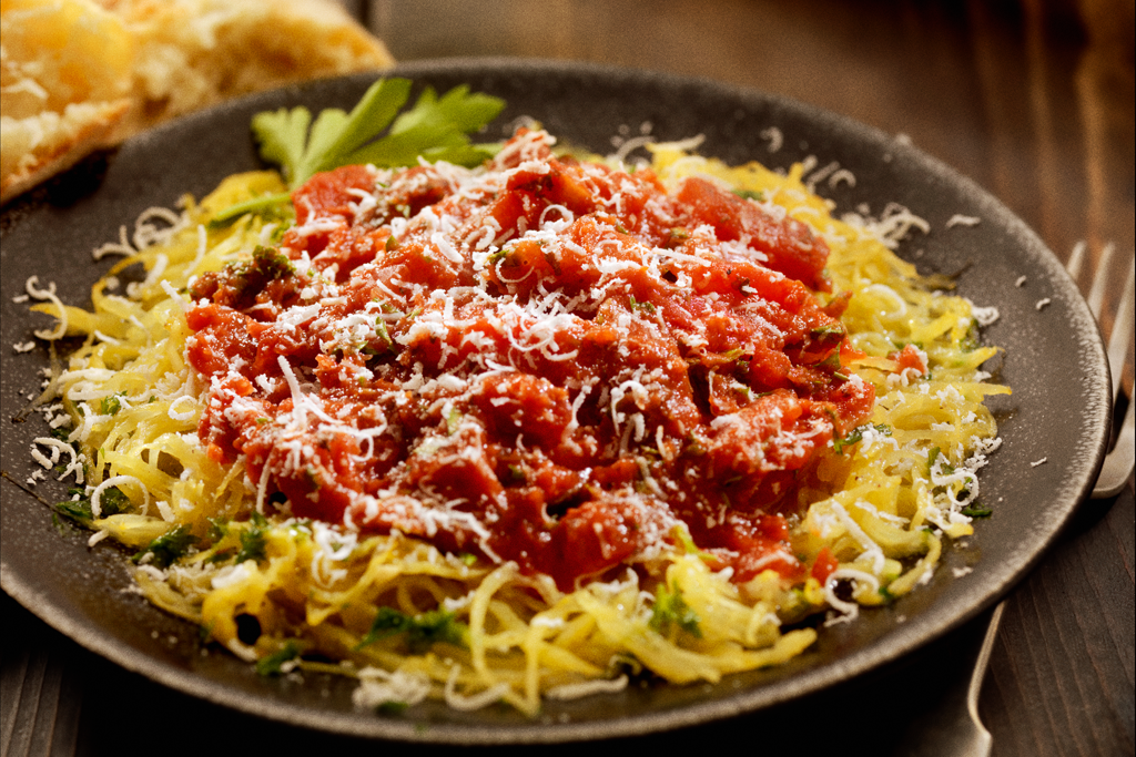 Zucchini spaghetti topped with sauce and cheese on a plate. 