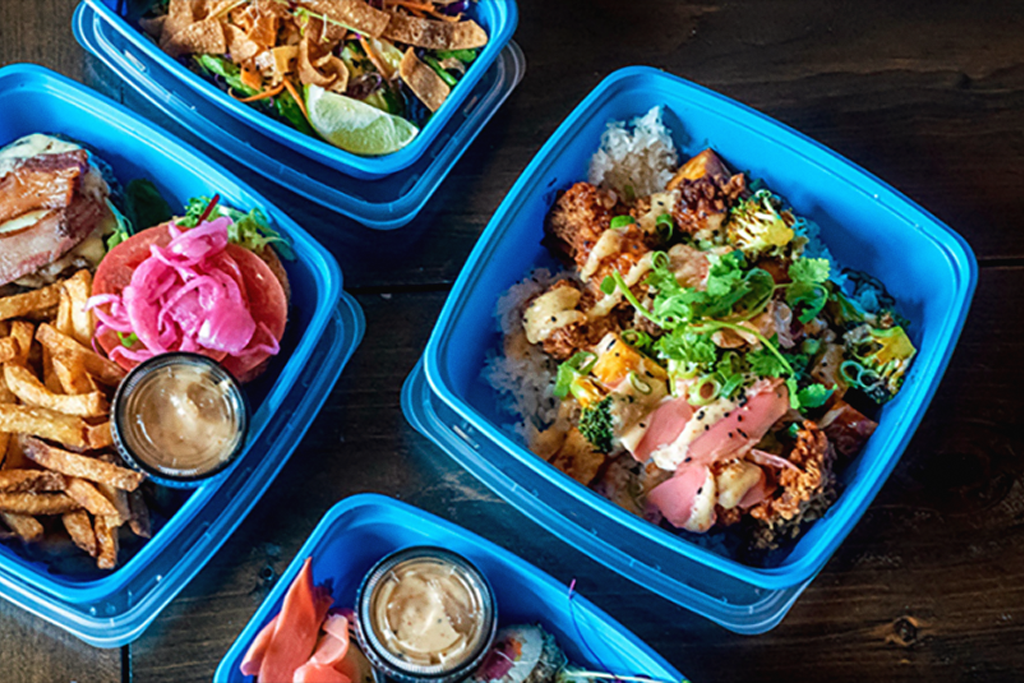 4 blue takeaway containers filled with an assortment of food.