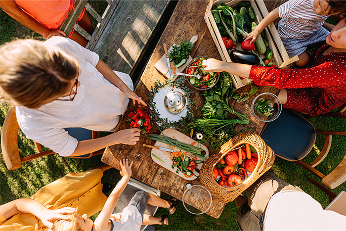 Above shot of people gathered around a wooden table with vegetables on it.