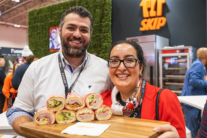 Sarah and Artin Davoodi, owners of local Toronto restaurant Grandma Loves You, holding their signature sandwiches in Skip’s booth on day 2 of the 2023 RC Show.