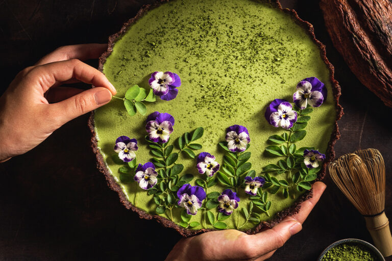 Matcha cake decorated with edible purple flowers.