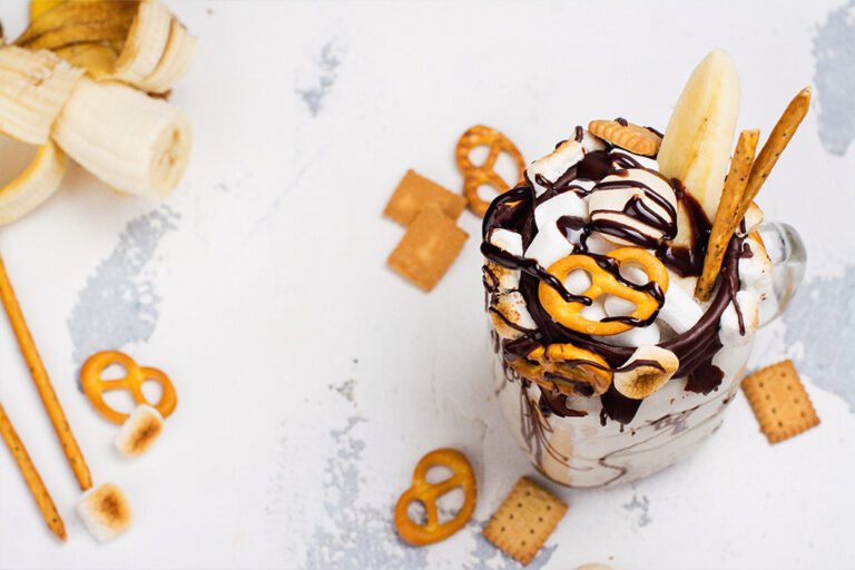 A mason jar with ice cream, drizzled with chocolate sauce and garnished with savoury pretzels.