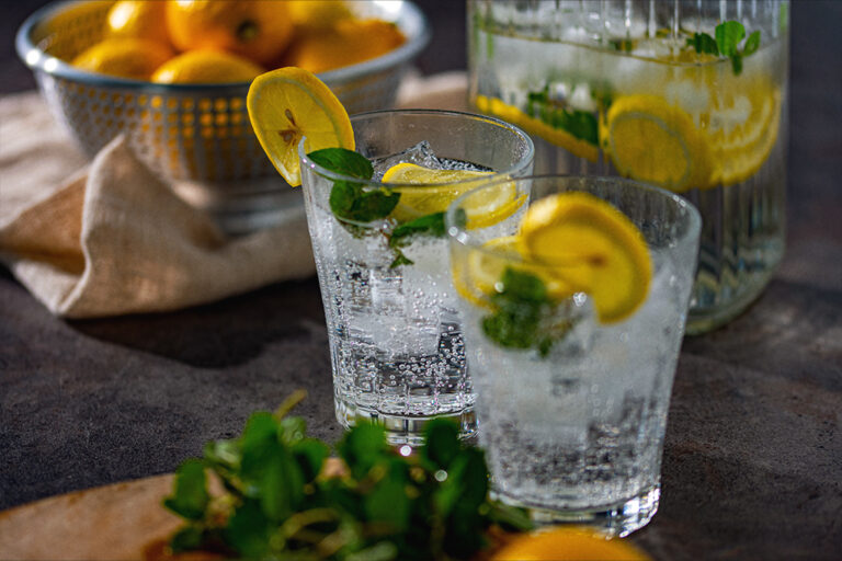 A pitcher and couple of glasses of refreshing lemon sparkling water garnished with mint.