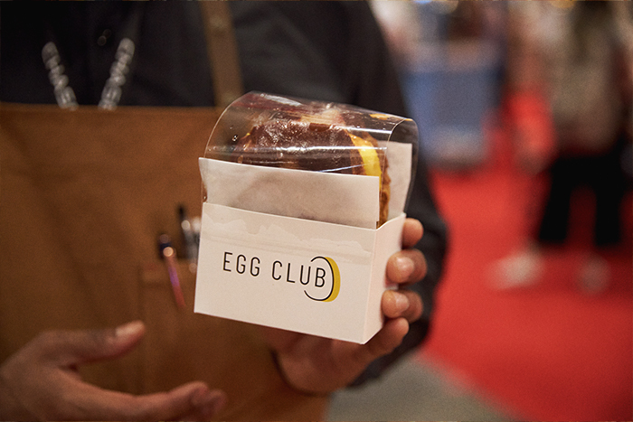 One of Egg Club’s signature sandwiches being held by a patron at the 2023 Restaurants Canada show.